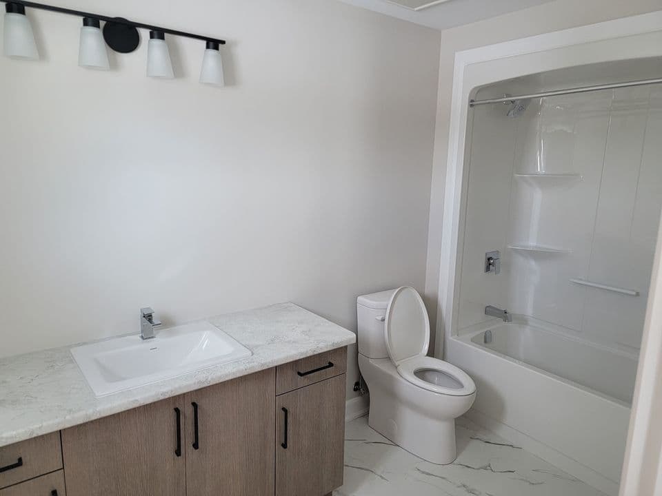 Full bathroom with tub and shower surround and a stone-top vanity