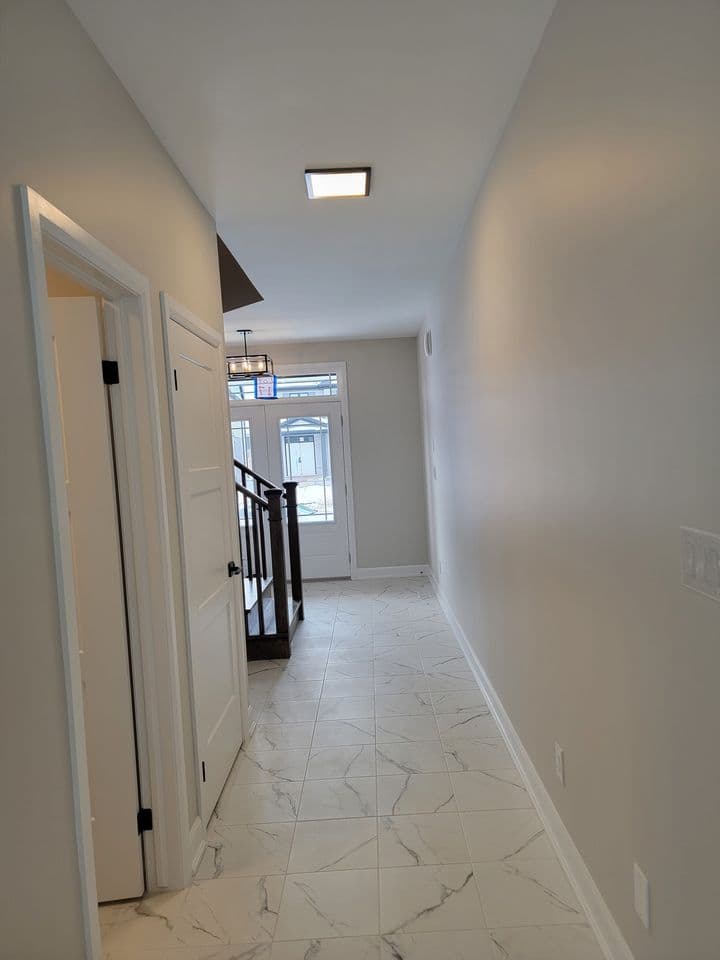 Main floor hallway in marble-look tile looking toward the front entry