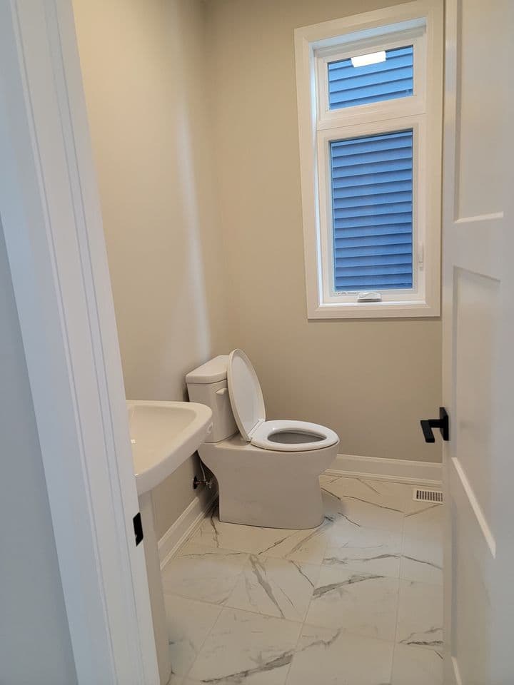 Main floor powder room with pedestal sink and marble-look tile
